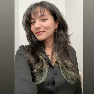 Woman with long dark hair and green highlights wearing a black shirt.